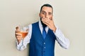 Young man with beard drinking a glass of white wine covering mouth with hand, shocked and afraid for mistake Royalty Free Stock Photo