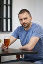 A young man with a beard drinks beer from a glass in a cafe Royalty Free Stock Photo