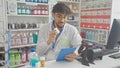 A young man with a beard examines medication while working in a pharmacy and using a tablet Royalty Free Stock Photo