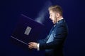 Young man with beard holding book and magic light on dark background Royalty Free Stock Photo