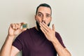 Young man with beard holding cpu computer processor covering mouth with hand, shocked and afraid for mistake Royalty Free Stock Photo