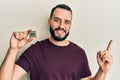 Young man with beard holding cpu computer processor smiling happy pointing with hand and finger to the side Royalty Free Stock Photo