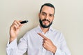 Young man with beard holding removable memory usb smiling happy pointing with hand and finger Royalty Free Stock Photo