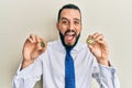 Young man with beard holding virtual currency ethereum coin and bitcoin celebrating crazy and amazed for success with open eyes