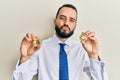 Young man with beard holding virtual currency ethereum coin and bitcoin looking at the camera blowing a kiss being lovely and sexy