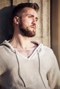 Young man with beard leaning against a wall