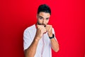 Young man with beard listening to music using headphones ready to fight with fist defense gesture, angry and upset face, afraid of