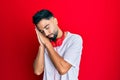 Young man with beard listening to music using headphones sleeping tired dreaming and posing with hands together while smiling with Royalty Free Stock Photo