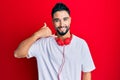 Young man with beard listening to music using headphones smiling doing phone gesture with hand and fingers like talking on the Royalty Free Stock Photo