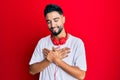 Young man with beard listening to music using headphones smiling with hands on chest with closed eyes and grateful gesture on face Royalty Free Stock Photo