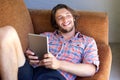 Young man with beard lying on sofa with digital tablet