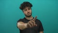 Young man with beard makes dismissive gesture against blue background looking serious and focused his gesture implies decision or Royalty Free Stock Photo