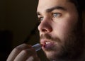 Young man with a beard repairing his damaged lips with moisturizer