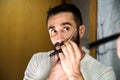 Young man with a beard shaving with a traditional knife in front of the mirror Royalty Free Stock Photo