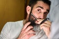 Young man with a beard shaving with a traditional knife in front of the mirror Royalty Free Stock Photo