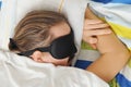 Young man with beard sleeping with sleep mask in bed