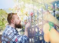 Young man with a beard and sunglasses smelling magnolia flower behind the fence, creating soft background of the urban landscape