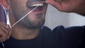 Young man with beard is using dental floss to clean his teeth. Close-up of man flossing his teeth. Mouth health care Royalty Free Stock Photo