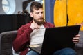 Young man with beard using laptop and holding glasses Royalty Free Stock Photo