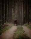 Young man with a beard walking towards a camera in a narrow forest path holding his camera Royalty Free Stock Photo