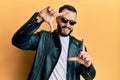 Young man with beard wearing black leather jacket and sunglasses smiling making frame with hands and fingers with happy face Royalty Free Stock Photo