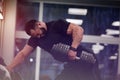 young man with beard wearing black sport clothes lifting heavy weight dumbbell with on hand training back in gym workout Royalty Free Stock Photo