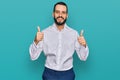 Young man with beard wearing business shirt success sign doing positive gesture with hand, thumbs up smiling and happy Royalty Free Stock Photo