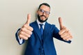 Young man with beard wearing business suit and tie approving doing positive gesture with hand, thumbs up smiling and happy for Royalty Free Stock Photo