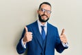 Young man with beard wearing business suit and tie success sign doing positive gesture with hand, thumbs up smiling and happy Royalty Free Stock Photo