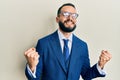 Young man with beard wearing business suit and tie very happy and excited doing winner gesture with arms raised, smiling and Royalty Free Stock Photo