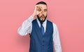 Young man with beard wearing business vest doing ok gesture shocked with surprised face, eye looking through fingers Royalty Free Stock Photo