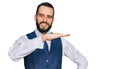 Young man with beard wearing business vest gesturing with hands showing big and large size sign, measure symbol Royalty Free Stock Photo