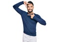 Young man with beard wearing casual blue winter sweater smiling making frame with hands and fingers with happy face Royalty Free Stock Photo