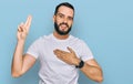 Young man with beard wearing casual white t shirt smiling swearing with hand on chest and fingers up, making a loyalty promise Royalty Free Stock Photo