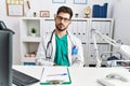 Young man with beard wearing doctor uniform and stethoscope at the clinic looking sleepy and tired, exhausted for fatigue and Royalty Free Stock Photo