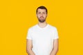 Young man with a beard in a white t-shirt with a serious expression on his face. Simple and natural looking into the camera. Royalty Free Stock Photo