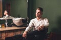 A young man with a beautiful hairstyle sits in a chair in a barbershop Royalty Free Stock Photo