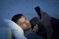 Young man in bed couch at home late at night using mobile phone in low light relaxed in communication technology concept Royalty Free Stock Photo