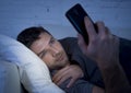 Young man in bed couch at home late at night using mobile phone in low light relaxed in communication technology concept Royalty Free Stock Photo