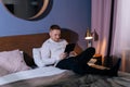 Young man on bed reading with e-book reader at home before sleeping. Royalty Free Stock Photo