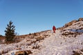 Young man from behind in red winter clothes hiking and climbing the mountain against the blue sky in winter Royalty Free Stock Photo