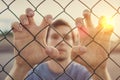 Young man behind wired fence. Immigration concept