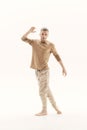 A young man in a beige jumper and cargo pants on a white background