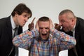 Young man being yelled at by two senior male manager on white