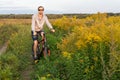 Young man on bicycle in field with flowers