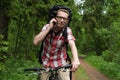 Young man on a bicycle talking in the forest on a mobile phone.