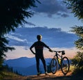 Young man with a bike enjoying sunset in the mountains Royalty Free Stock Photo
