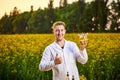 A young man biologist or agronomist examines the quality of rapeseed oil on a rape field. Agribusiness concept Royalty Free Stock Photo