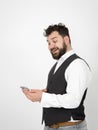 Young man with black beard is posing and looking at his smartphone in front of white background with different emotions Royalty Free Stock Photo