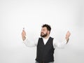 Young man with black beard is posing and looking at his smartphone in front of white background with different emotions Royalty Free Stock Photo